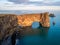 Amazing black arch of lava standing in the sea. Location cape Dyrholaey, Iceland