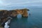 Amazing black arch of lava standing in the sea on small peninsula.