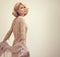 Amazing blond beautiful woman with bob curly short hair style posing in fashion silk clothing and golden dress on studio