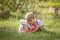 Amazing blond toddler child, boy with pet dog, eating watermelon in garden