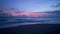 Amazing blue pink violet tropical sunset at ocean shore. Waves of sea rolling on beach at dark twilight. Last sun rays
