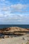 Amazing blue skies with wispy clouds over large rocks and beach chair at shoreline