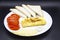 Amazing breakfast with tasty omelet, tomatoes, cheese, bread and sauce on the white plate. Delicious omelet made like rolle, other