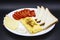 Amazing breakfast with tasty omelet, tomatoes, cheese, bread and sauce on the white plate. Delicious omelet made like rolle, other