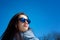 Amazing brunette with mirrored sunglasses outdoors over blue sky during early spring time.