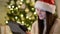 Amazing Brunette in Santa Hat Touching a Screen of Her Tablet at Christmas Decorated Home and Smiling. Emotional Woman