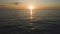 Amazing calm aerial footage of sunset in the ocean. Sun glow at dusk reflecting in the waves of dark sea. Drone flying