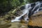 Amazing cascading tropical waterfall. wet and mossy rock, surrounded by green rain forest