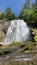 Amazing Chatterbox Waterfall in Princess Louisa Marine Park surrounded by trees and blue skies.