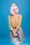 Amazing cheerful young woman in luxury clothes on blue background. Cut pink hair, golden sweater, grey tulle skirt