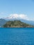 The amazing Choshuenco Volcano surrounded by clouds, over the waters of Lake Panguipulli, in southern Chile