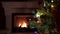 Amazing Christmas tree blinking colorful lights garland near fireplace with burning fire log