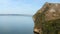 Amazing cliff covered trees and grass near calm water of river in sunny day