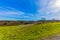 Amazing contrast on a sunny day of a green grass with an arid terrain with a wonderful blue sky