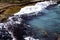 Amazing crystal clear beach blue water of the ocean. Big tidal waves hitting shoreline and rock formation. Windy countryside area.