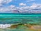 Amazing crystal clear blue water on a paradise beach - small wave - rocky island in the background