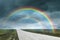 Amazing double rainbow over road under stormy sky, blurred view