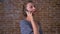 Amazing emotional caucasian brunette girl is talking over phone and standing still near red brick wall