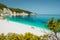 Amazing Fteri beach lagoon, Cephalonia Kefalonia, Greece. Tourists under umbrella relax near clear blue emerald turquise