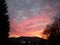 Amazing glow fiery colors in the sky over the dark silhouettes of plants and trees after a summer sunset in the countryside.