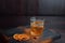 Amazing golden Scotch whiskey in a crystal glass decorated with sweet orange slices and peanuts, stands on an old wooden table