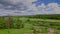 Amazing green summer nature landscape view. View buildings on green fields between green forest trees under blue sky.