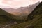 Amazing and hard summer mountain landscape - panorama view on mountain valley with dark peaks with glaciers, green hilly slopes