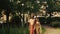 Amazing Indian bride in red and gold wedding costume stands behind a groom in the garden