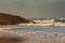 Amazing landscape on the Atlantic ocean at sunrise. View of foamed waves running ashore sandy beach and birds flying around in sky