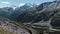 Amazing landscape with giant mountains with green slopes and snowy peaks. Clip. Stony trail along rocks covered by green