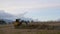 Amazing landscape of tractor excavator works in field and digs trench under boundless blue sky with clouds