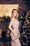 Amazing luxury seductive woman in stylish golden party dress posing on Christmas decoration background