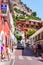 Amazing medieval Positano cityscape on rocky landscape, people and tourists walking by the cozy streets full of local businesses