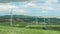 Amazing panorama of green field with spinning windmills, mountains on horizon