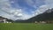 Amazing panorama of green valley with houses and Dolomites mountain range, Italy