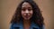 Amazing portrait of happy calm beautiful gen-z mixed race 20-25 woman with curly hair posing at camera slow motion.