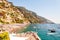 Amazing Positano cityscape on rocky landscape, people on the beach, boats are coming and going to the sea tours, promenades full