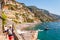 Amazing Positano cityscape on rocky landscape, people on the beach, boats are coming and going to the sea tours, promenades full