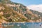 Amazing Positano cityscape on rocky landscape, people on the beach, boats are coming and going to the sea tours, promenades full