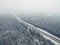Amazing road in the frozen winter forest with driving cars. Foggy vanishing point perspective. Aerial panoramic view on the north
