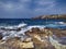 Amazing seascape with blue rough sea crashing on rocky bay with lot of foam, a blue sky with soft white cirrus clouds