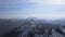 Amazing shot from drone of mountain range peaks covered in white snow. Aerial view through fog of hills on morning of