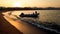 Amazing silhouette photo of inflatable boat with motor rocking on calm ocean waves at the sandy shore against sunset sky