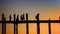 Amazing silhouettes of monks on the ancient wooden bridge at sunset sky background. Burma, Mandalay