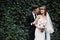 Amazing smiling wedding couple. Pretty bride and stylish groom. groom and bride posing in front wall with green ivy