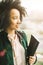 Amazing stylish brazil woman in green jacket standing next to the window