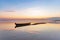 Amazing sunrise. Lonely boat in calm lake. The silhouette is reflecting on the water. Beautiful summer day. Blue sky with clouds.