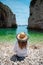 Amazing symmetrical view of a brunette from behind, Stiniva beach on the island of Vis in Croatia. Crystal clear green teal sea,