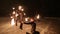 Amazing tribal fire show dance at night on winter under falling snow. Dance group performs with torch lights and