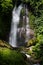 Amazing tropical cascade waterfall in wild green forest with powerful stream of water in sunbeams with water splashes and lush.